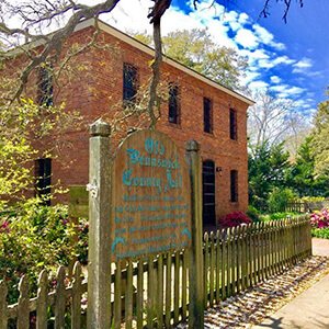 Old Jail Museum building with wooden sign and picket fence