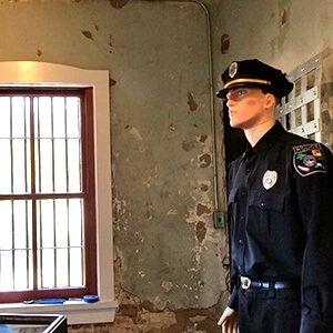 Uniformed police officer mannequin by a barred jail window